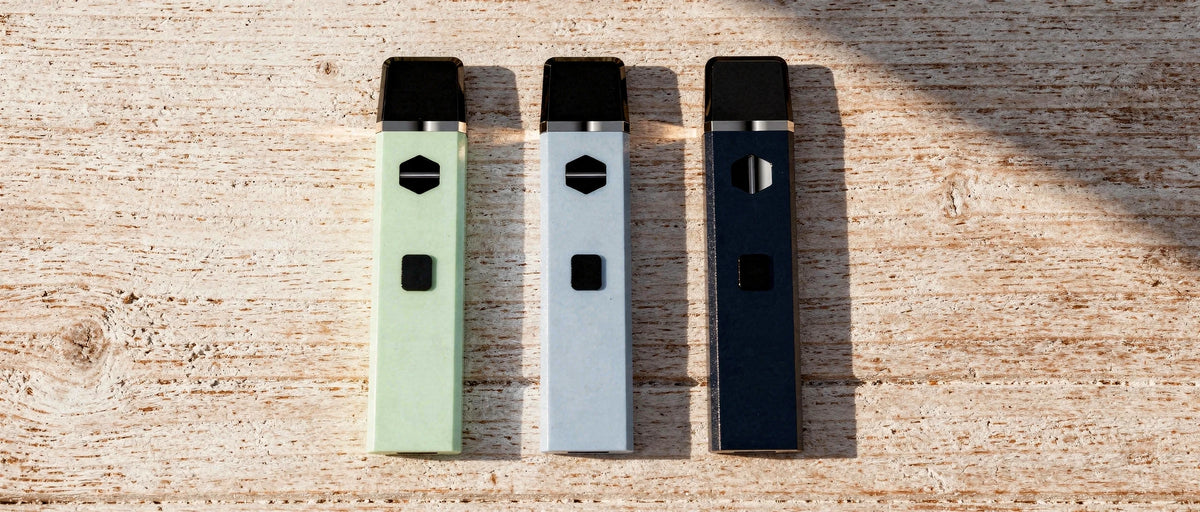 Drei Einweg-Vapes in verschiedenen Farben nebeneinander auf hellem Holz, Symbolbild zu DNT-9 Erfahrungen